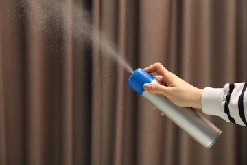 Woman spraying air freshener indoors, closeup. Space for text