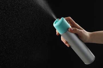 Woman spraying air freshener on black background, closeup. Space for text