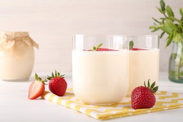 Tasty yogurt and strawberries in glasses on white wooden table, closeup