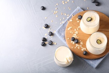Tasty yogurt in glasses, oats and blueberries on grey table, above view. Space for text