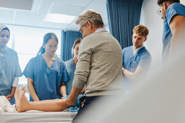 Senior health practitioner training medical students using a patient simulator in a hospital