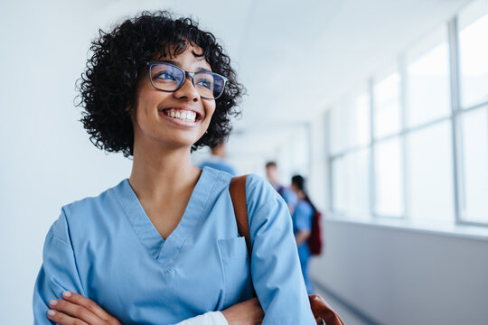 Confident medical intern smiles in a training hospital, wearing scrubs