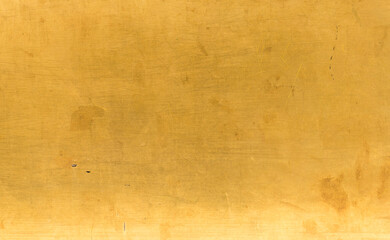 Artificial Gold background and texture on cement make from color paint for look like real gold. Gold foil leaf dirty abstract background texture distress scratch and gradients shadow in Gold glitter