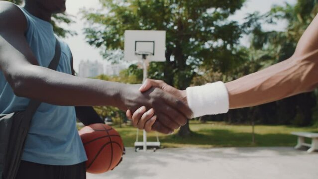 Cropped shot of streetball players shaking hands while meeting on playground