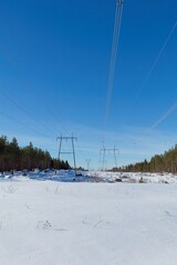 Fototapeta na wymiar High-voltage power lines in sunny winter weather with snow on the ground, Loviisa, Finland.