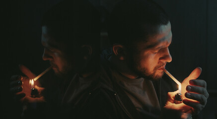 Handsome bearded man smoking cigarette sitting in the dark room. Hipster with lighter and cigarette. Closeup.