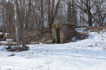 Old abandoned brick cellar under the ground in winter.