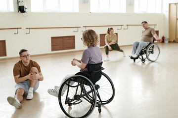 Selective focus shot of modern dancers with disabilities in wheelchairs and their partners doing...