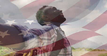 Naklejka premium Image of american flag moving over man widening his arms on beach