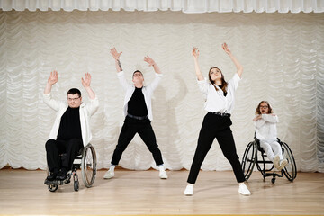 Group four diverse people performing contemporary wheelchair dance on stage, long shot, copy space