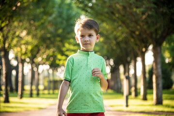 Awesome young happy boy portrait. The cute little kid is in the park posing wearing casual clothes