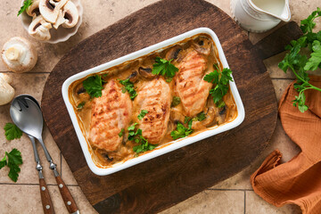 Baked chicken breast bbq with mushrooms and garlic in cream sauce on old brown concrete tilestable backgrounds. Top view image with ingredients for cooking. Top view with copy space.