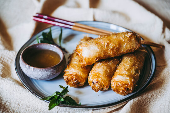 Nems au poulet accompagn&eacute; de sauce piquante et feuilles de salade et menthe fraiche