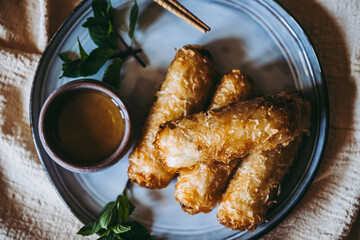 Nems au poulet accompagn&eacute; de sauce piquante et feuilles de salade et menthe fraiche