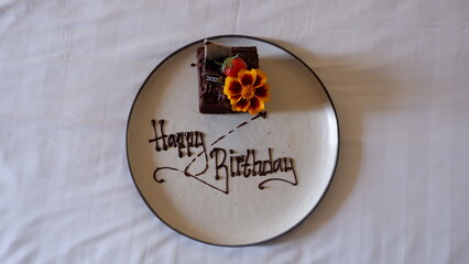 a plate of a cute little birthday cake on the bed