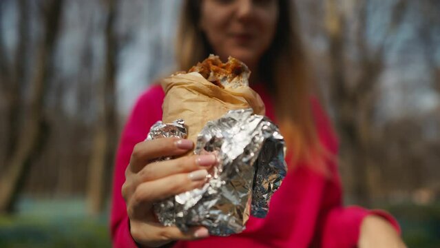 Woman holding a burrito wrapped in tin foil as a fashionable accessory