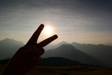 Catching the sun with fingers and blurred Karwendel mountainsin the background, Alps, Tyrol,...