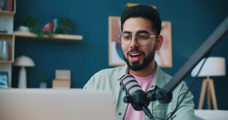 Vlogger working at recording room. Male blogger discussing latest new live. Podcasting or broadcasting. Man leading blog. Vlogger reading aloud viewers comments. Recording equipment. - Powered by Adobe