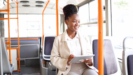 Happy woman using tablet while riding in a bus