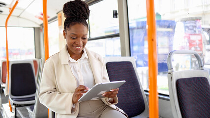 Happy woman using tablet while riding in a bus
