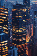 Fototapeta na wymiar A closeup of skyscrapers in a city during nighttime using a telephoto lens