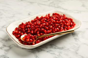 Ripe juicy pomegranate grains on white marble table