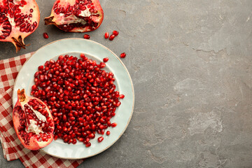 Tasty ripe pomegranate and grains on grey table, flat lay. Space for text