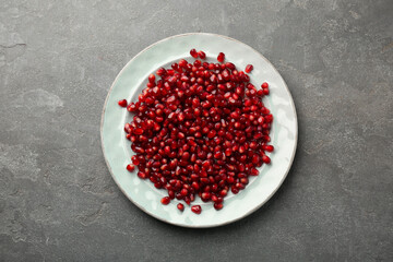 Tasty ripe pomegranate grains on grey table, top view