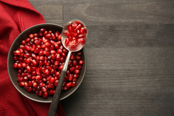 Tasty ripe pomegranate grains on dark wooden table, top view. Space for text