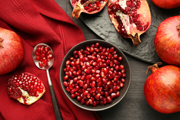Tasty ripe pomegranates and grains on dark wooden table, flat lay