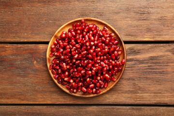 Tasty ripe pomegranate grains on wooden table, top view