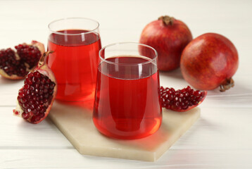Tasty pomegranate juice in glasses and fresh fruits on white wooden table