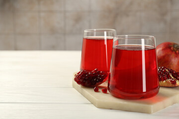 Tasty pomegranate juice in glasses and fresh fruits on white wooden table, closeup. Space for text