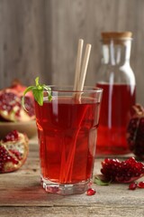 Tasty pomegranate juice in glass and fresh fruits on wooden table