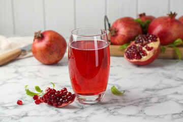 Tasty pomegranate juice in glass and fresh fruits on white marble table