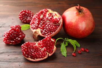 Fresh pomegranates and green leaves on wooden table