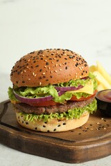 Burger with delicious patty, french fries and sauce on light table, closeup