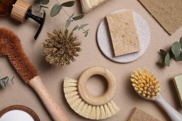 Cleaning brushes, soap, sponge and eucalyptus leaves on pale brown background, flat lay