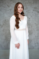 Fototapeta na wymiar portrait of beautiful young woman in white wedding dress posing in studio.