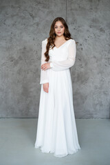 Fototapeta na wymiar portrait of beautiful young woman in white wedding dress posing in studio.