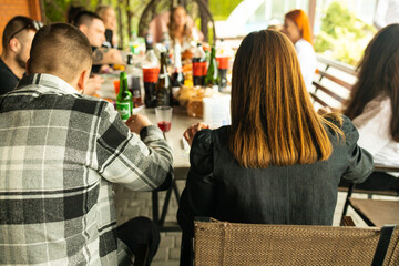 Back view of young people sitting at a table in a restaurant.