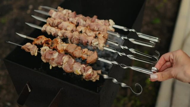 Person grilling shish kebabs on a grill, a type of brochette recipe