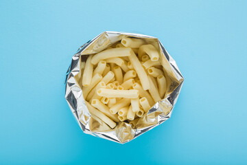 Opened foil bag of white potato chips sticks on light blue table background. Pastel color. Closeup. Top down view. - 785292641