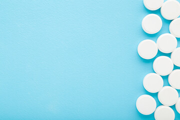 White pills of c vitamins on light blue table background. Pastel color. Closeup. Nutritional supplements. Empty place for text. Top down view.
