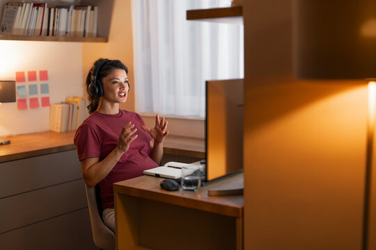 A dedicated mid adult pregnant woman having a video call with her colleagues on her computer at home - Powered by Adobe