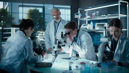 Young Team of Science Researchers Sitting Behind a Table, Using Microscopes for Medical Pharmaceutical Research and Treatment Development. Senior Scientist Supervising the Project - Powered by Adobe