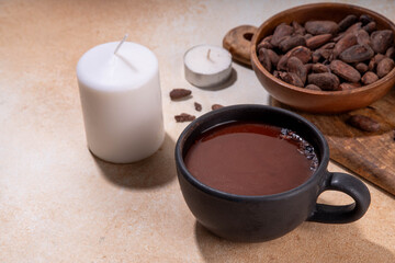Ceremonial Cacao drink. Hot ceremonial chocolate in black cup with cocoa beans. Woman hands holding cocoa mug. Organic healthy chocolate drink prepared from beans, without creamer, sugar or toppings - 785295230