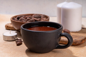 Ceremonial Cacao drink. Hot ceremonial chocolate in black cup with cocoa beans. Woman hands holding cocoa mug. Organic healthy chocolate drink prepared from beans, without creamer, sugar or toppings - 785295239