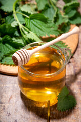 Nettle Tea hot plant drink in transparent glass cup. Organic natural herbal tea without caffeine, made with organic raw nettle leaves. Alternative herbal medicine. Stinging nettles, urtica.