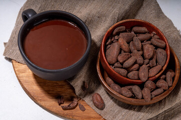 Ceremonial Cacao drink. Hot ceremonial chocolate in black cup with cocoa beans. Woman hands holding cocoa mug. Organic healthy chocolate drink prepared from beans, without creamer, sugar or toppings - 785296012